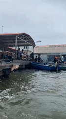 Blue boat departs Ibasa waterfront past industrial shoreline