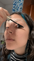 Woman applies makeup while filming herself in Gijón bathroom