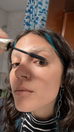 Woman applies makeup while filming herself in Gijón bathroom