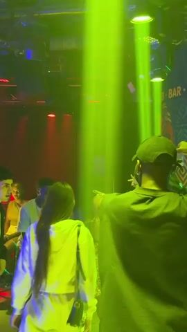 The video shows a group of young people dancing in a nightclub. The club has colorful lights and a banner that says "CLUB 07 RESTAURANT."  Some of the people are wearing casual clothing, while others are dressed up in club wear. One person in a black shirt is raising their arms and dancing enthusiastically. The atmosphere is energetic.