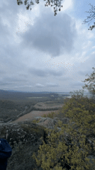 Two men observe valley landscape from rocky outcrop in Bulgaria