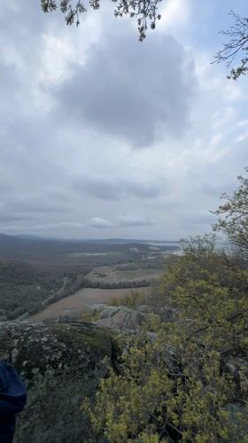 Two men observe valley landscape from rocky outcrop in Bulgaria