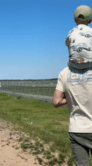 Father and child watch planes from field in Latvia