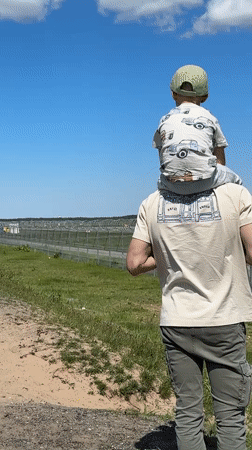 Father and child watch planes from field in Latvia