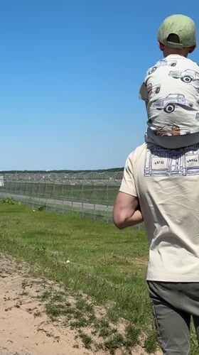 Father and child watch planes from field in Latvia