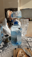 Woman drinks from large water bottles while eating pickles in Budva