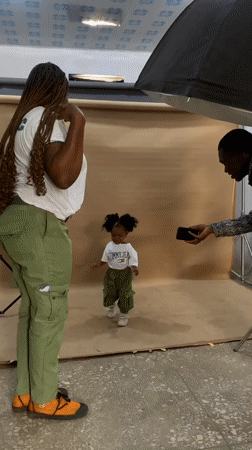 Woman in NYSC uniform poses with child in Nigerian studio