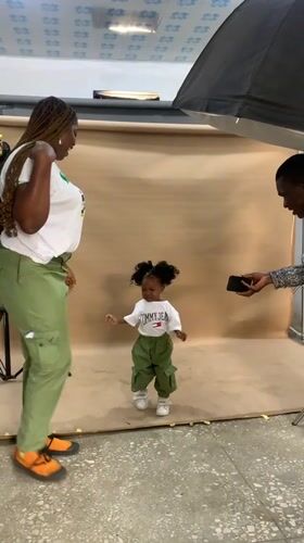 Woman in NYSC uniform poses with child in Nigerian studio