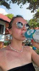 Woman drinks pH PLUS water at Thai beach location