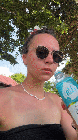 Woman drinks pH PLUS water at Thai beach location