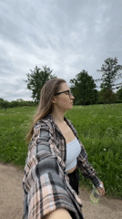 Woman enjoys park stroll amid wildflowers in overcast Saint Petersburg