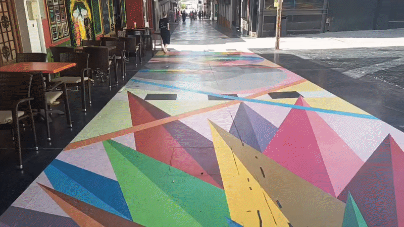 Pedestrian passes vibrant geometric street art in Spanish town