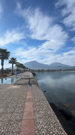 Woman records herself walking along waterfront path in Fethiye
