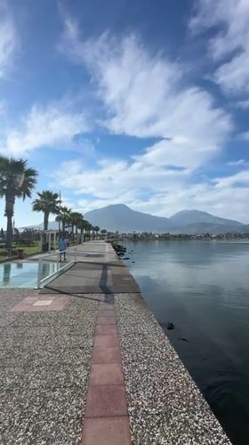 Woman records herself walking along waterfront path in Fethiye