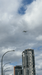 City streets, skyscrapers, and planes on a partly cloudy afternoon