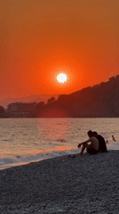 Fethiye beach at golden hour — sunset, paddleboards, and pebble shore.