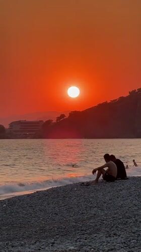 Fethiye beach at golden hour — sunset, paddleboards, and pebble shore.