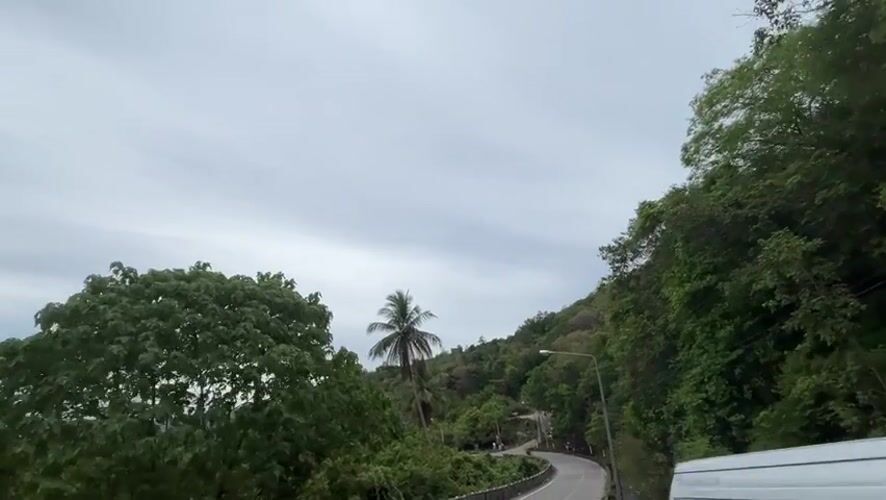 Motorcycle journey through lush tropical hillside roads in Thailand
