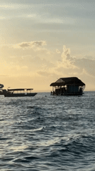 Boat passengers wave near traditional sea platform off Nusa Penida