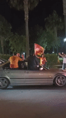 Four people celebrate with flag in convertible BMW in Turkey