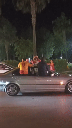 Four people celebrate with flag in convertible BMW in Turkey