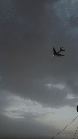 Aircraft spotted through cloudy skies over Delhi rooftops