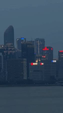 Illuminated skyline observed across water in Shangcheng District
