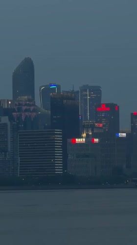 Illuminated skyline observed across water in Shangcheng District