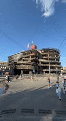 Damaged building documented amid normal street life in Kyiv