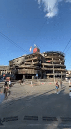 Damaged building documented amid normal street life in Kyiv