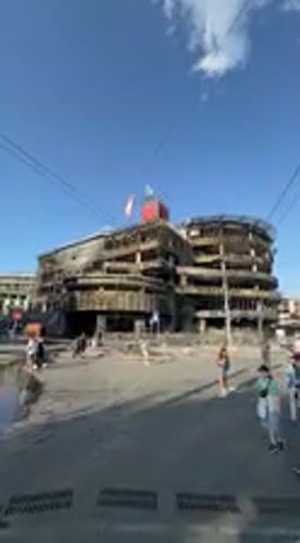 Damaged building documented amid normal street life in Kyiv
