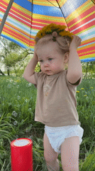 Toddler plays under umbrella in Vladimir field