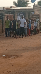 Children and adults gather in line on residential dirt road