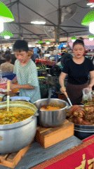 Food vendors serve customers at busy Thai market