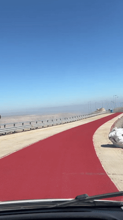 Vehicle travels red-painted road section near Arica, Chile
