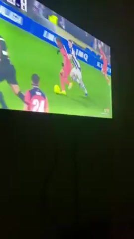 A recording shows a TV screen displaying a soccer match in progress. The score is 0-0, and the time is 17:41. Players in opposing uniforms of red and black are running on a green field. The stadium is filled with spectators. The camera focuses on the back of a player wearing a red jersey with the number 10 and the name "LAMINE YAMAL." A QR code is present on the lower portion of the screen for real-time match stats. A black cord hangs in front of the screen.