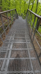 Person walks down metal staircase in forest setting
