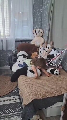 Toddler plays with stuffed pandas on bed in Russia