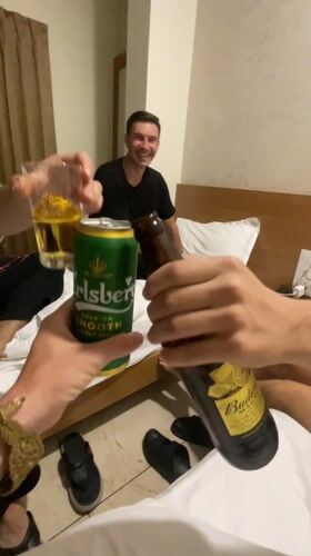 Three men toast drinks in Kolhapur hotel room