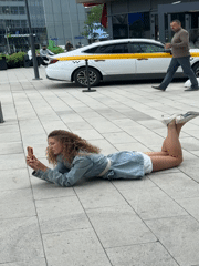 Woman lies on pavement using phone in Khimki