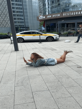 Woman lies on pavement using phone in Khimki