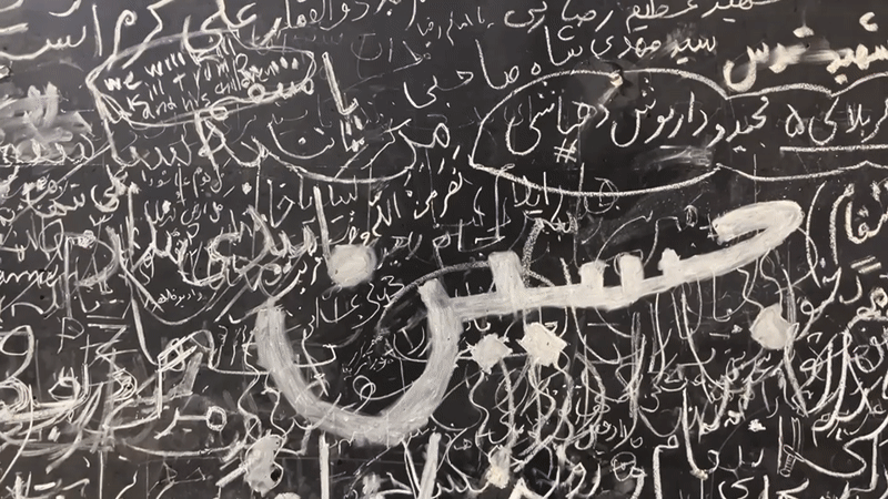Chalk-covered wall in Tehran draws people writing and paying tribute