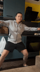 Woman dances in kitchen while dogs watch in Bulgaria