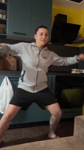 Woman dances in kitchen while dogs watch in Bulgaria