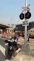 Train crosses intersection in Đà Nẵng with motorcycle nearby