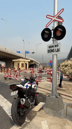 Train crosses intersection in Đà Nẵng with motorcycle nearby