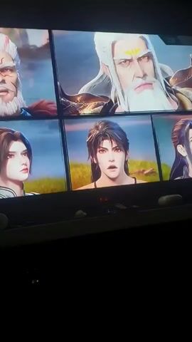 The video shows a television screen displaying a scene from an animated show. In the first frame, a figure with blonde hair and a golden outfit is facing a glowing blue sphere within which stands a taller, more detailed figure with dark hair and similar clothing. Chinese characters appear briefly above the figures. The second frame displays an outdoor scene. A group of characters are standing in a grassy area near a body of water and some trees. The subtitles read, “Master, please, you must save the Divine Lord!” The video is shot from a low angle, showing a cluttered shelf below the television.