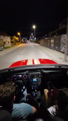 Group drives red convertible through Bar, Montenegro at night