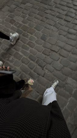 Two people stroll cobblestone street in Gdańsk