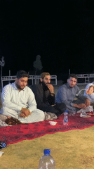 Nighttime outdoor meal on a red rug in rural Afghanistan